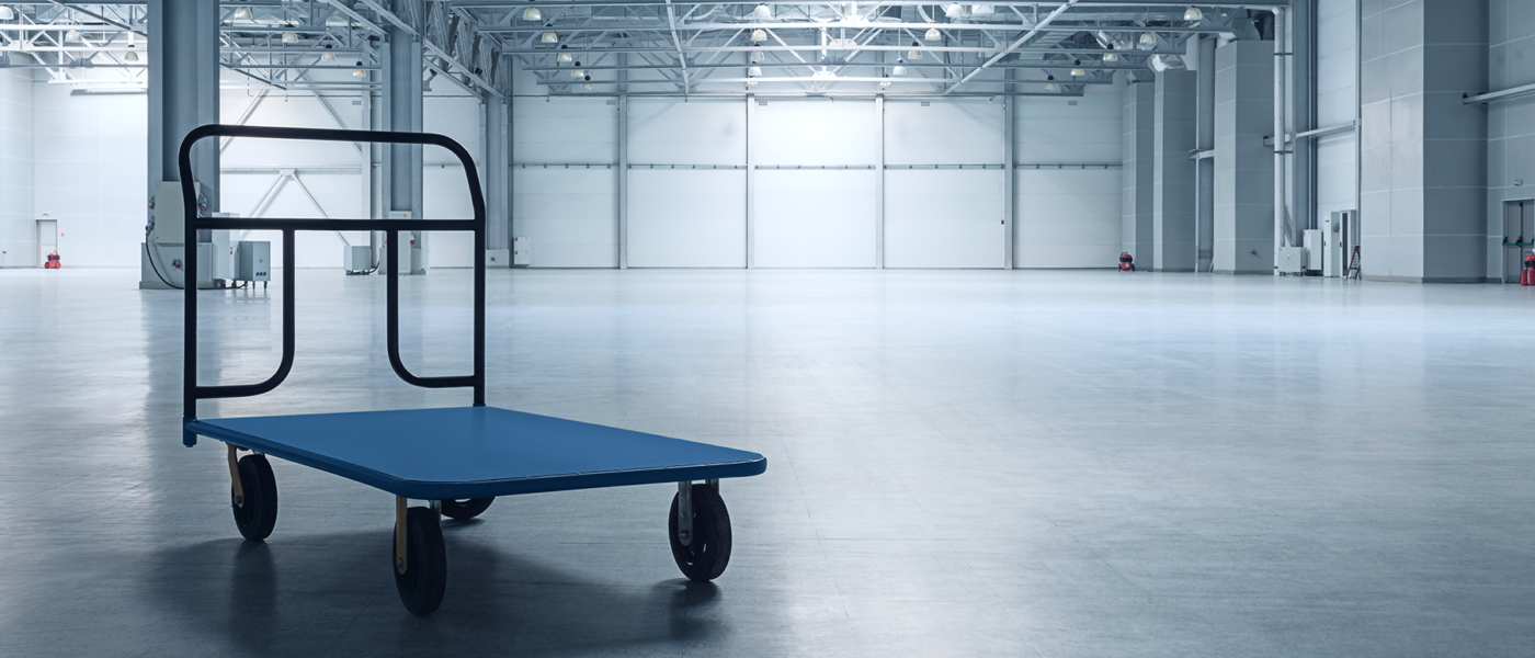 A hand truck sits inside an empty warehouse space.