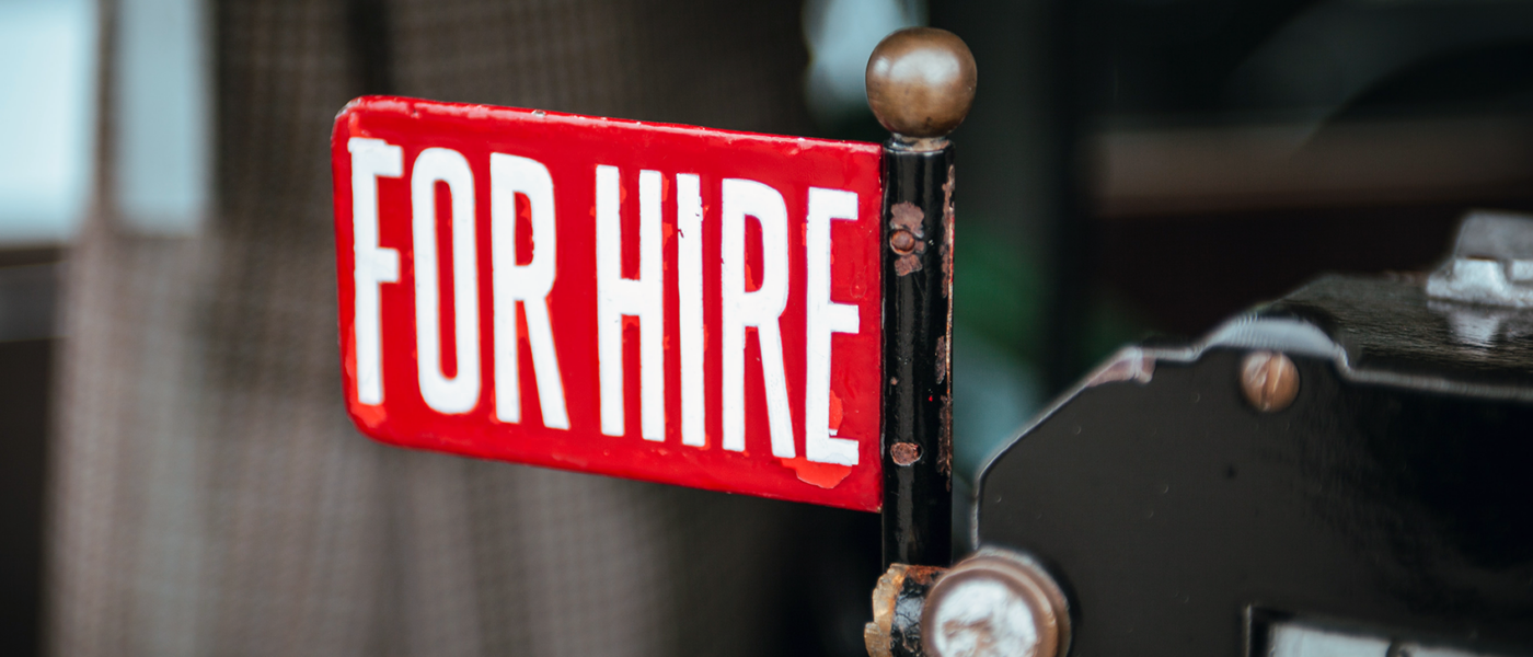 An old taxi sign with a red label that reads, "For Hire"