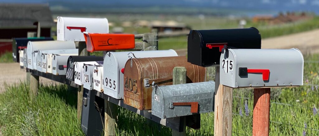 white and red mailboxes on a wooden rail